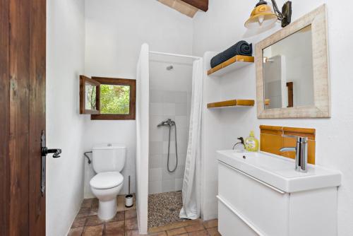 La salle de bains est pourvue de toilettes, d'un lavabo et d'un miroir. dans l'établissement Casa Sa Mata, à Artà