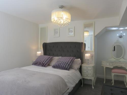 a bedroom with a large bed and a chandelier at Esk Cottage - Cyanacottages in Whitby
