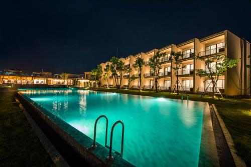 a swimming pool in front of a building at night at The Gallery Hotel Nai Harn in Nai Harn Beach