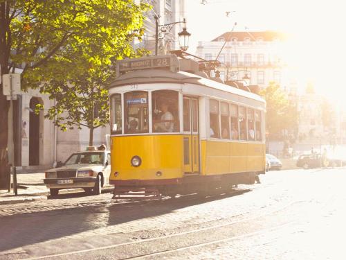 a yellow trolley car driving down a city street at The ART INN Lisbon in Lisbon