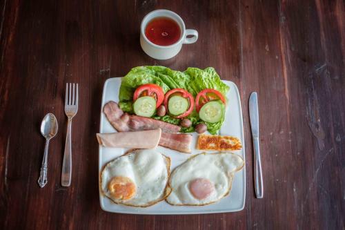 a plate of food with eggs meat and vegetables and a cup of tea at Saint Antonio Maroni in Maroni