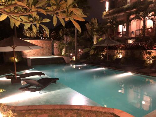 a swimming pool with chairs and umbrellas at night at Betutu Bali Villas in Ubud