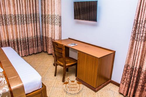 a room with a desk and a bed and a bed and a bedskirts at Grand Winston Hotel in Nakuru
