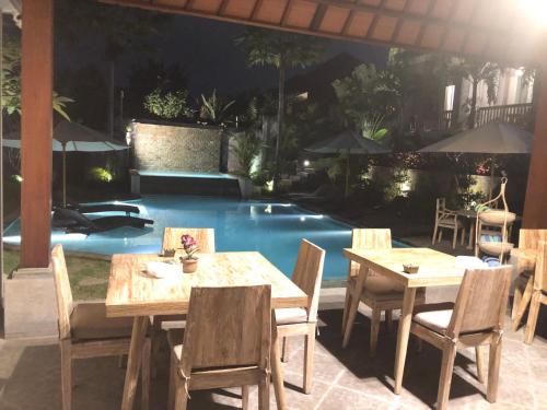 a patio with tables and chairs next to a pool at Betutu Bali Villas in Ubud