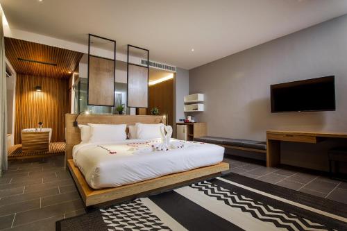 a bedroom with a large bed and a flat screen tv at The Gallery Hotel Nai Harn in Nai Harn Beach