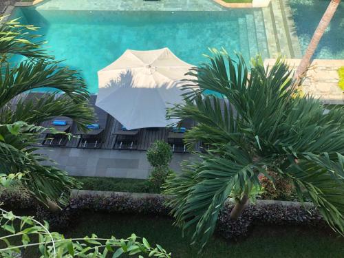 a pool with a white umbrella and palm trees at Betutu Bali Villas in Ubud