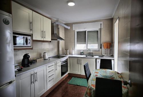 a kitchen with white cabinets and a table in it at Canto da Maia Apartment in Ponta Delgada