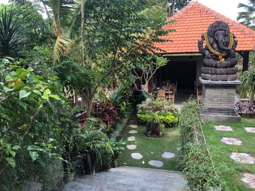 a garden with a statue in front of a building at Betutu Bali Villas in Ubud