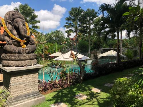a statue in front of a swimming pool with a resort at Betutu Bali Villas in Ubud
