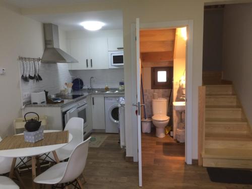 a kitchen with a table and white cabinets and a sink at La Llastra de Garaña in Llanes