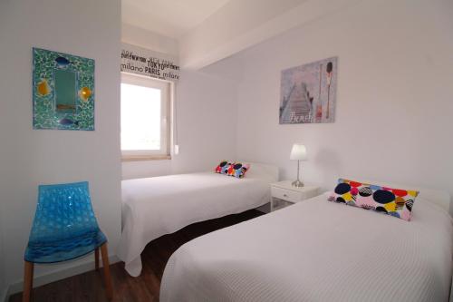 um quarto branco com duas camas e uma janela em House Beach em Costa da Caparica