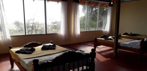 two beds in a room with large windows at 5 Mile Beach Resort in Kumta