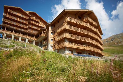 un grand bâtiment au sommet d'une colline dans l'établissement CGH Résidences & Spas les Chalets du Soleil Contemporain, aux Menuires