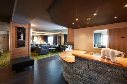 un hall d'hôtel avec une statue d'ours polaire sur un comptoir dans l'établissement CGH Résidences & Spas les Chalets du Soleil Contemporain, aux Menuires