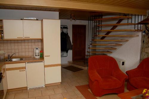 eine Küche mit einem roten Stuhl und einer Treppe in der Unterkunft Fewo Mühlehof in Königshain