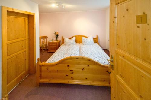 a bedroom with a wooden bed with white sheets at Hotel Garni Am Klostermarkt in Plauen
