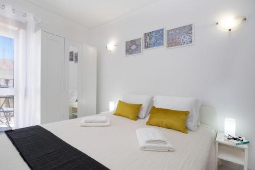 een witte slaapkamer met een groot bed met gele kussens bij Esquina do Mar in Armação de Pêra