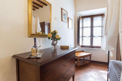 a dresser with a mirror and a vase of flowers on it at Locanda Il Porcellum in Bagno Vignoni