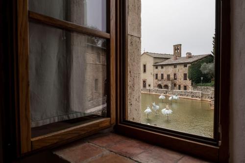 a window with a view of a group of white birds in the water at Locanda Il Porcellum in Bagno Vignoni
