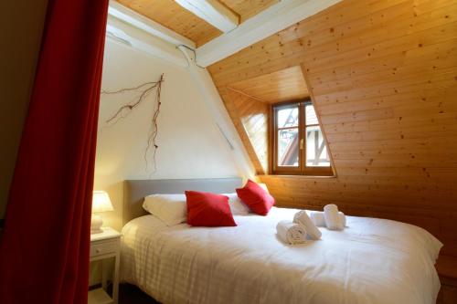 Schlafzimmer mit einem Bett mit roten Kissen und einem Fenster in der Unterkunft RIBEAUVILLE city center - Gîte des Ménétriers, LES VIEILLES VIGNES - in Ribeauvillé