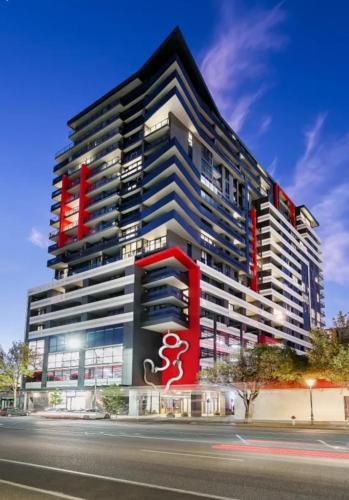 a tall building with a red sign in front of it at The Apartment Complex in Adelaide