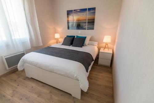 a bedroom with a large white bed with two lamps at La maison des gardiens de l'Océan & spa - Les Gîte de Fabie - Plougonvelin in Plougonvelin