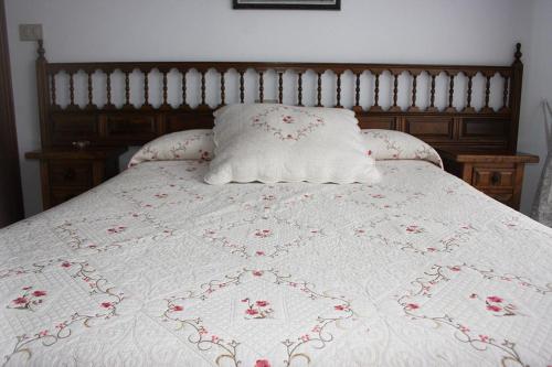 a bed with a white quilt with red flowers on it at PORTO MAR in Bares