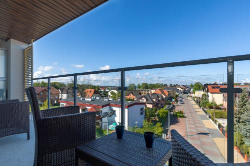 a balcony with tables and chairs and a view of a town at Apartamenty Słoneczne Tarasy by Renters in Dziwnówek