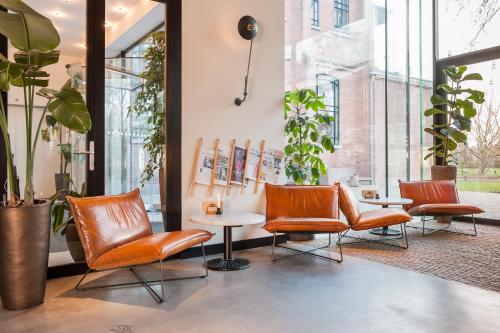a waiting area with chairs and tables and plants at Hotel Arena in Amsterdam