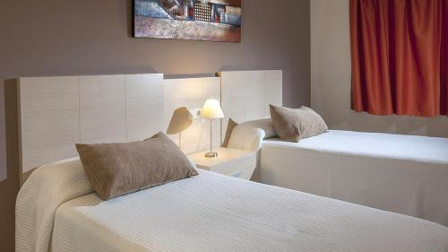 a hotel room with two beds and a lamp at ESTIMAR Calpe Apartments in Calpe