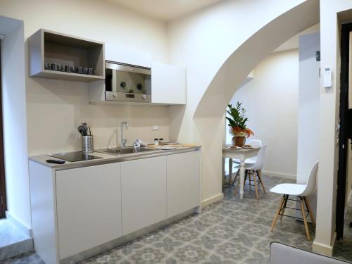 uma cozinha com armários brancos, um lavatório e uma mesa em Vuciata Apartments em Catânia