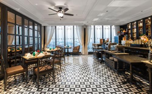 a restaurant with tables and chairs in a room with windows at La Siesta Premium Hang Be in Hanoi