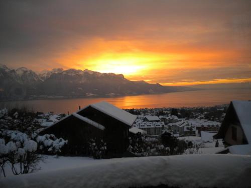 a winter sunset over a city with snow covered buildings at Appartement La Coudraie in Blonay