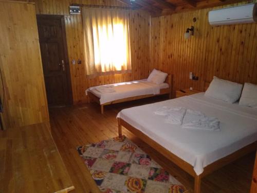two beds in a room with wooden walls and wooden floors at Ada Adrasan Hotel in Adrasan
