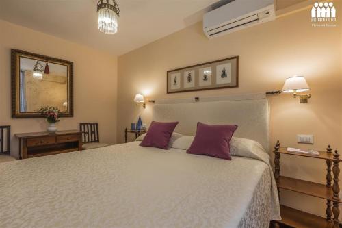 a bedroom with a large white bed with purple pillows at Ca' Cerchieri 1 Garden View in Venice