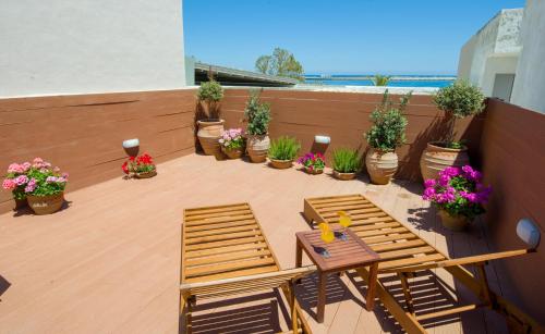 eine Terrasse mit Stühlen, Tischen und Topfpflanzen in der Unterkunft Elma Suites in Rethymno