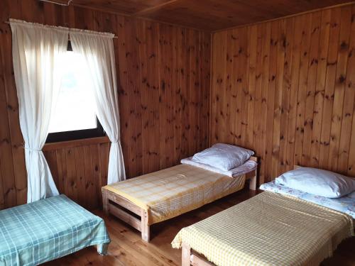 a room with two beds and a window in it at Domek Wieloosobowy - Agroturystyka in Przetycz