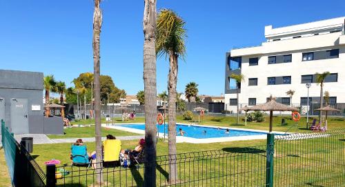 a group of people sitting in chairs near a swimming pool at Residencial Costa Doñana (Sanlucar de Barrameda) in Sanlúcar de Barrameda