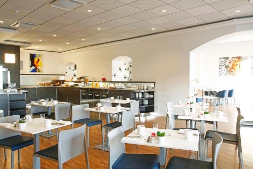 une salle à manger avec des tables et des chaises blanches dans l'établissement Hôtel Méditerranée, à Calvi