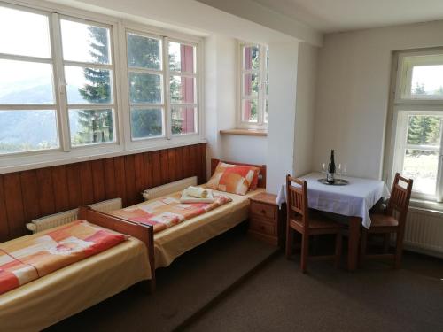 a room with two beds and a table and a table and chairs at Horská chata Sedmidolí in Špindlerův Mlýn