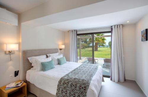 a bedroom with a bed and a large window at Tiamo Secrets - Palm Garden in Vourvourou