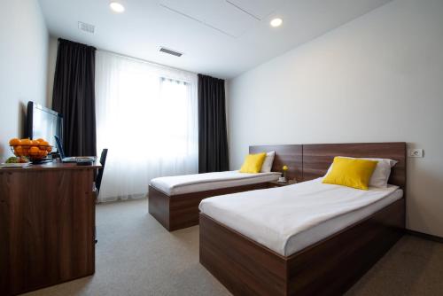 a bedroom with two beds and a desk and a window at Boca Boutique Hotel in Timişoara