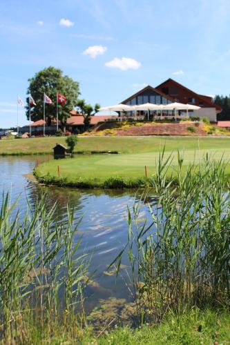 Hôtel Golf-Club Les Bois في Les Bois: اطلالة على ملعب قولف مع بركة