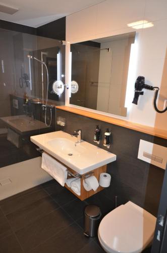 ein Badezimmer mit einem Waschbecken, einem WC und einem Spiegel in der Unterkunft Hôtel Golf-Club Les Bois in Les Bois