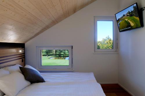 a bedroom with a bed and two windows at Hôtel Golf-Club Les Bois in Les Bois