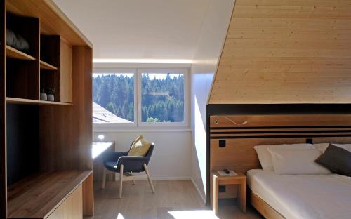 a bedroom with a bed and a desk and a window at Hôtel Golf-Club Les Bois in Les Bois