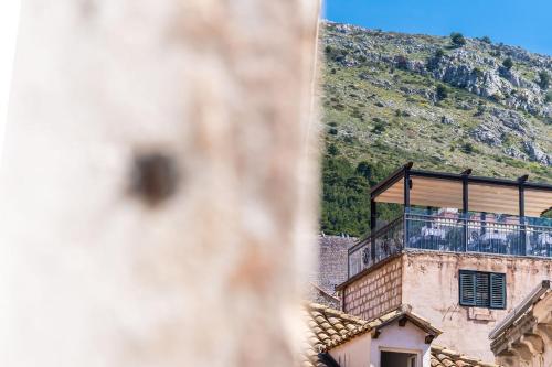 a building with a balcony with a mountain in the background at Rooms Katja & Lara in Dubrovnik