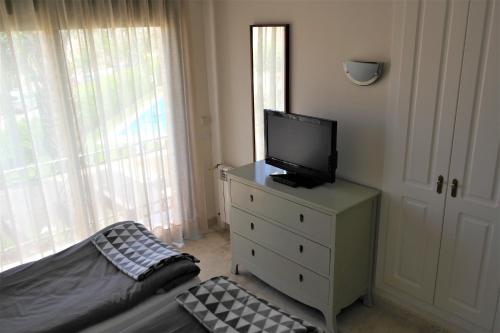 a bedroom with a dresser with a television on it at Townhouse overlooking the pool in San Javier