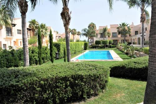 a swimming pool in a yard with palm trees and bushes at Townhouse overlooking the pool in San Javier