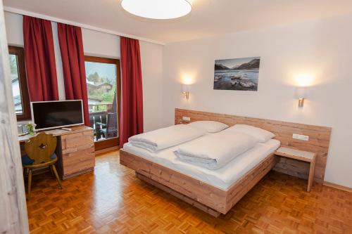 a bedroom with a large bed and a television at Pension Leuprecht in Reutte